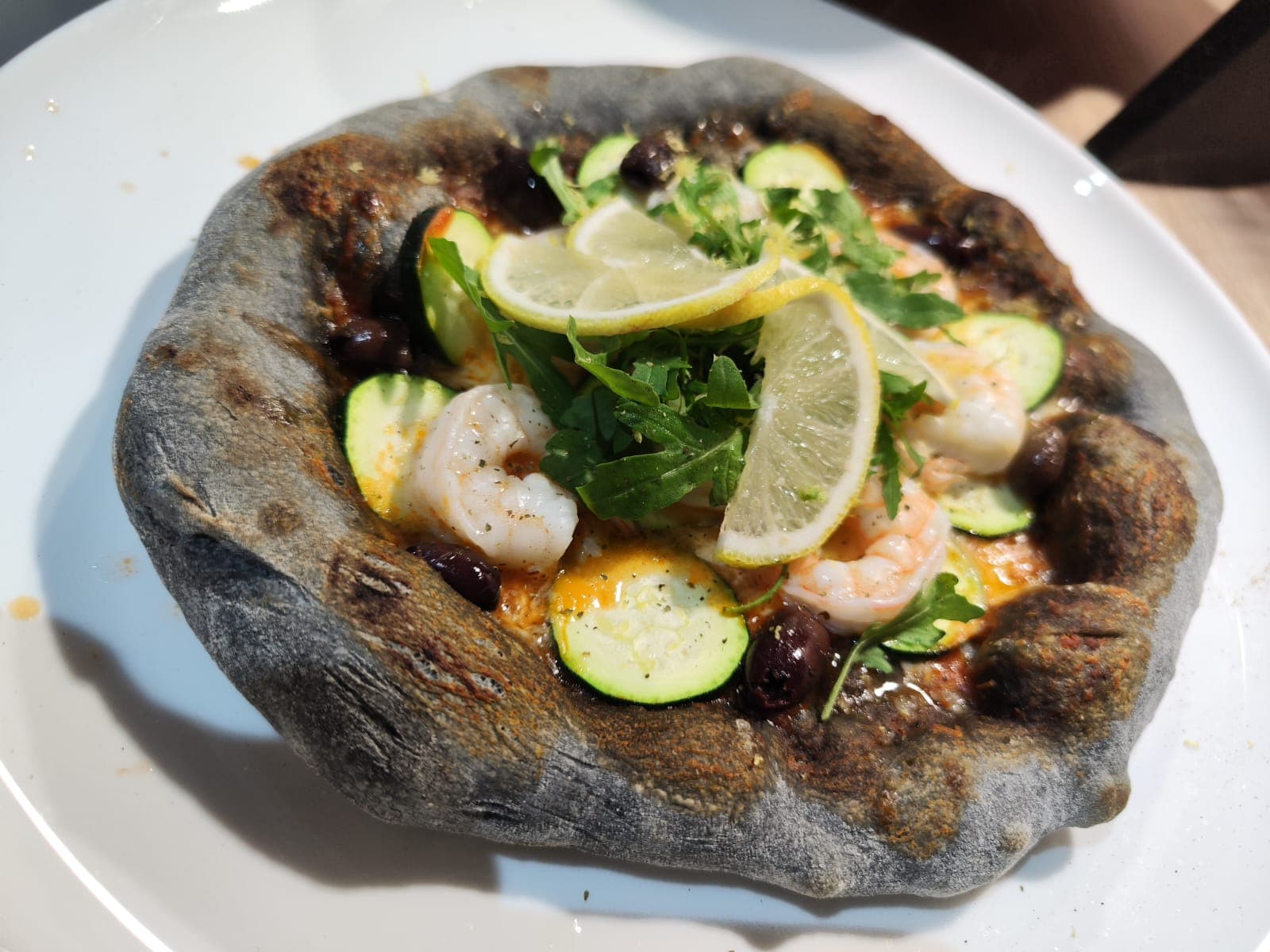 Schwarze Pizza mit Garnelen und Rucola – Spezialität des Hauses