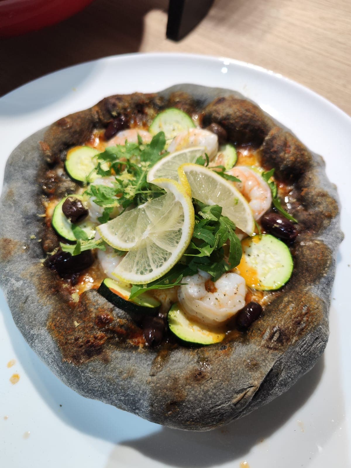 Schwarzer Pizzateig mit Garnelen, Zucchini und Zitronenscheiben